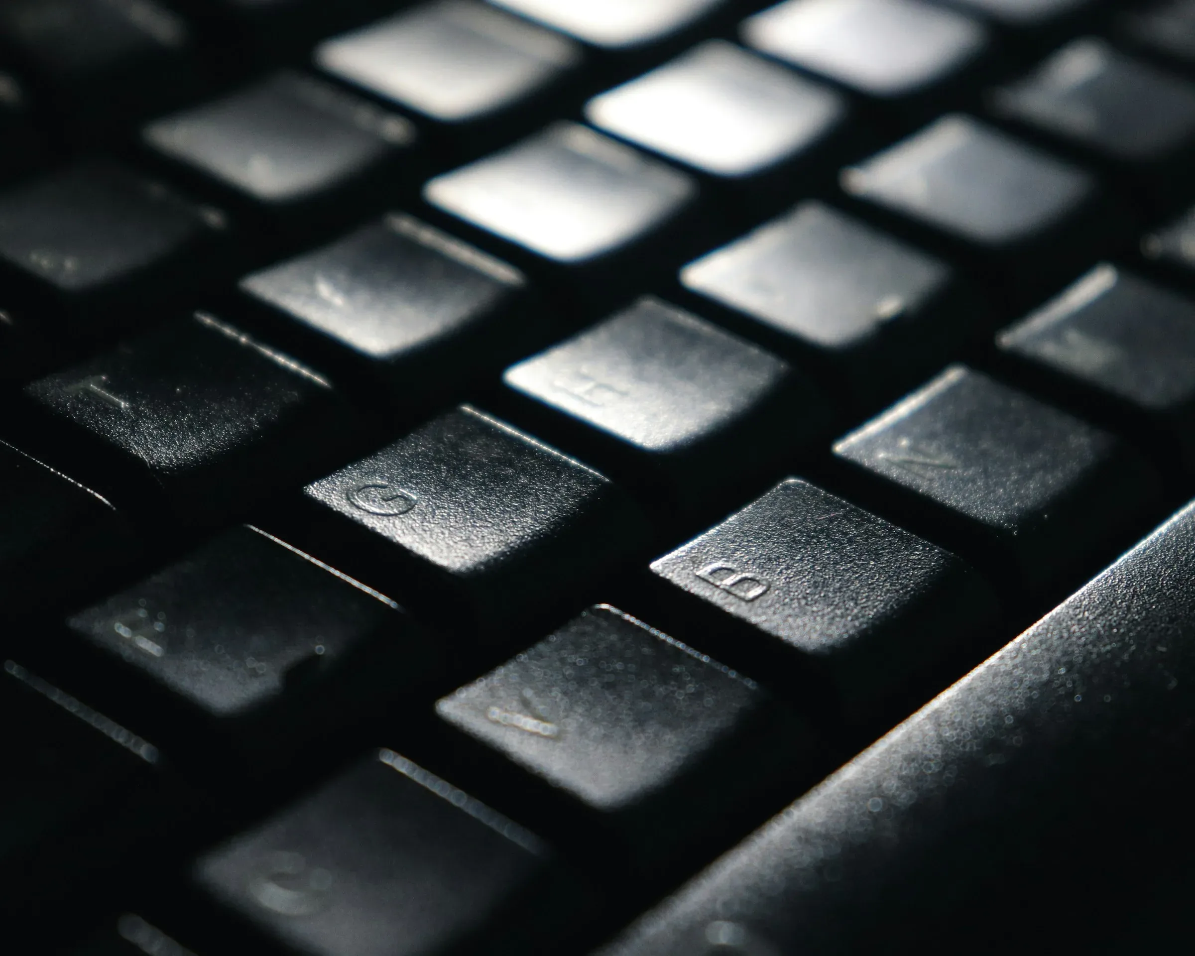 Close-up of a black backlit computer keyboard in low, even light — Zozzi B.V.